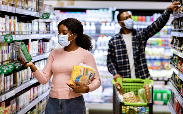 Couple grocery shopping with masks