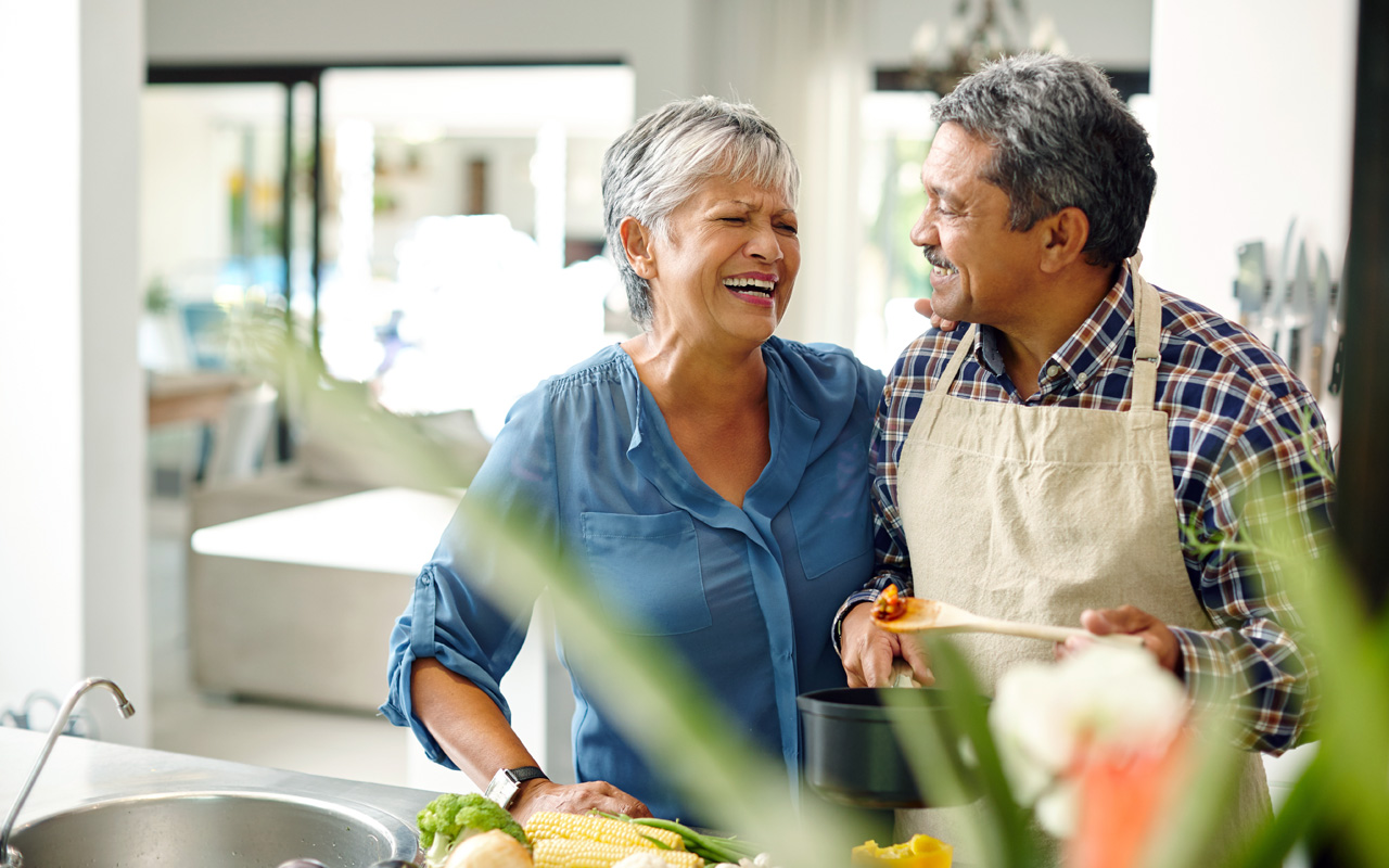 Older couple smiling at each other while cooking