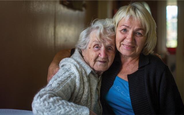 Elderly woman cheek-to-cheek with daughter