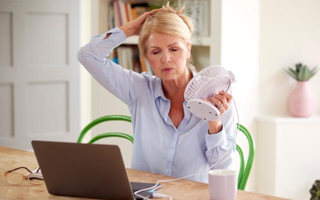 Woman using fan to try and stay cool