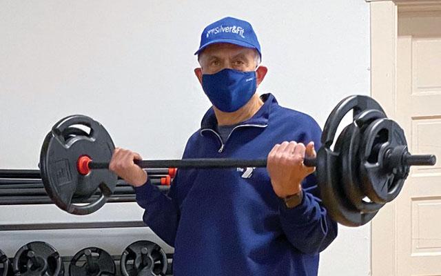 Ken Camilucci and Kristin Quinn lift weights while socially distant and wearing masks